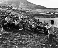 3058122 During a break, commune workers sing in pr