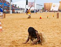 Indigenous girl plays in the sand as the spear thr