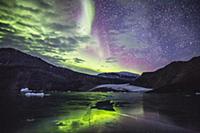 Aurora borealis over glacier and coastal mountains