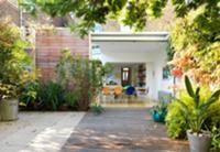 Wooden terrace with flower bed in front of house a