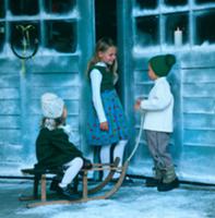 Three children with sledge in front of house