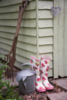 Wellies, watering can and garden tools next to she