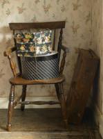 Old suitcase in corner & hatboxes on wooden chair