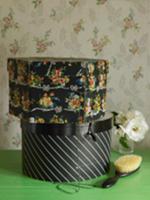 Two hatboxes on table in front of floral wallpaper