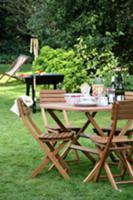 Set table in garden with chairs & barbecue in back