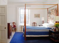 Bedroom with canopied bed, blue bedspread & blue r