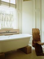 Free-standing modern bathtub supported on wooden b