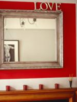 'Love' mirror with silver wooden frame on red wall