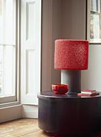 Lamp with red shade and red ornaments on modern ta