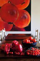 Bright red peppers and tomatoes on dark dining tab