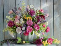 Colourful bouquet in glass vase against wooden wal