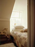 Patchwork quilt on bed in window niche of attic ro