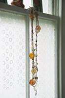 Necklace with flower motif hanging in front of win