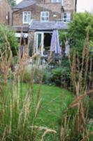 View through grasses of dining area on terrace of 