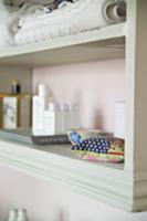 Old, white shelf with colorful mini-pillows and ba