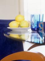 Lemons on a plate next to colored water glasses on