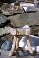 Rustic wooden footstool in front of boulders and a