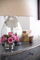 Posy of roses in glass vase in front of table lamp