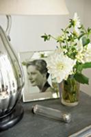 White flowers in glass vase next to framed photogr