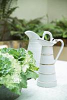 Antique, white-painted jugs next to plant pot