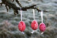 Three painted Easter eggs hanging on branch of app