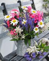 Summer bouquet in a zinc pitcher on a garden bench