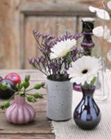 Flower vases and plums on a wooden table