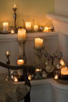 Various lit candles on candle sticks and holders i