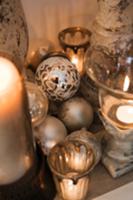 Silver Christmas baubles next to candle holders wi