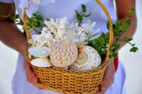 Woman holding basket containing seashells and wedd