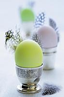 Coloured eggs and feathers in egg cups