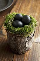 Easter eggs in moss nest on wooden surface