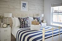 Double bed with white metal frame and white-and-bl