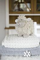 Plush sheep on stack of woollen blankets