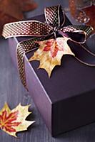 Gift box decorated with ribbon and autumn leaf pen