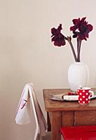 Deep red amaryllis in white vase on wooden table