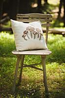 Mushroom-patterned cushion on chair in sunny woodl