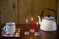 Three lit red candles in cake-shaped candle holder