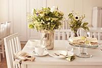 Table set with coffee, cake and vases of flowers