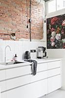 Whit fitted kitchen with exposed brick wall