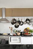 Pans hung on wall above kitchen counter, gas cooke