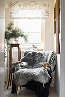 Grey sheepskin blanket on armchair in front of win