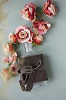 Fabric roses and bottle tied with leather bow on g