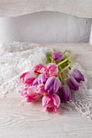 Pink and purple tulips on lace doily on white chai