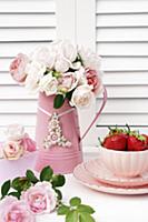 Metal jug of delicate pink roses and china bowl of