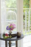 Small vase of flowers under antique glass cover