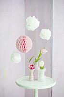 Pompoms and paper honeycomb ball above tulips in v