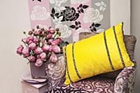 A purple velvet chair with a yellow cushion, vase 