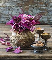 Moth orchids and astilbes in golden bowl