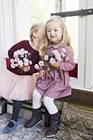 Two girls holding flowers and whispering